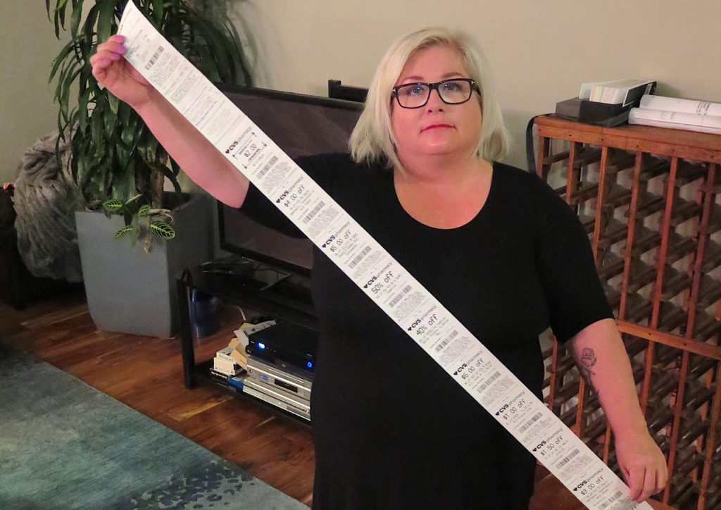 Carol Dahmen poses with a receipt that's more than 4 feet long—for the purchase of a single item. Photo via Kevin Eckery for CALmatters