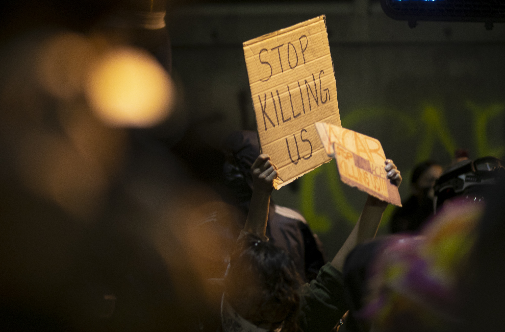 A protester holds up a sign that says ‘stop killing us’ during a demonstration May 29, 2020 Downtown Oakland. Thousands took to the streets Friday night in solidarity with protesters in Minneapolis against the killing of George Floyd by Minneapolis police earlier this week. Photo by Anne Wernikoff for CalMatters
