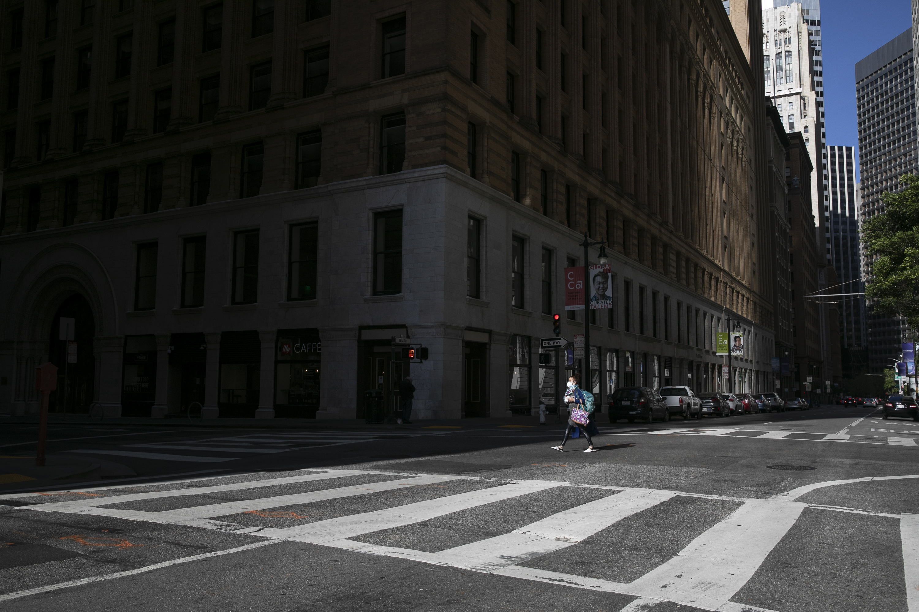 A pedestrian crosses an empty intersection in San Francisco financial district at evening rush hour on May 7, 2020. Photo by Anne Wernikoff for CalMatters