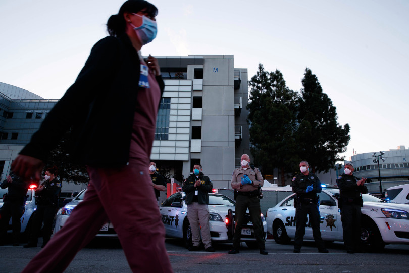 Medical workers walk into the Santa Clara Valley Medical Center in San Jose on April 15 as first responders show gratitude by clapping and cheering them on at. In an ironic twist, some health care workers across California are facing layoffs and furloughs. Photo by Randy Vazquez / Bay Area News Group