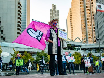 Martha Hubert, a CodePink organizer, waves a peace flag a Nov. 4 rally in Embarcadero Plaza in San Francisco. Hubert said she feared violence may break out as election controversy escalated. Photo by Brian Howey for CalMatters