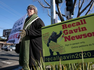 Recall Newsom volunteer Kerin Kay holds up a sign during a petition signing event at SaveMart in Sacramento on Jan. 5, 2021. Photo by Anne Wernikoff, CalMatters