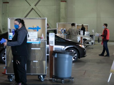 Los miembros de la Guardia Nacional y el personal médico administran las vacunas COVID a los trabajadores de la salud en un sitio de distribución de autoservicio en Cal Expo en Sacramento el 21 de enero de 2021. Foto de Anne Wernikoff, CalMatters