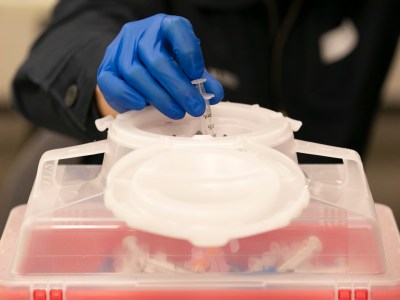 Alameda County Fire Department employee Max Shih dispenses of a syringe after administering a Moderna COVID-19 vaccine during a distribution clinic at St. Rose hospital in Hayward on Jan. 27, 2021. Photo by Anne Wernikoff, CalMatters