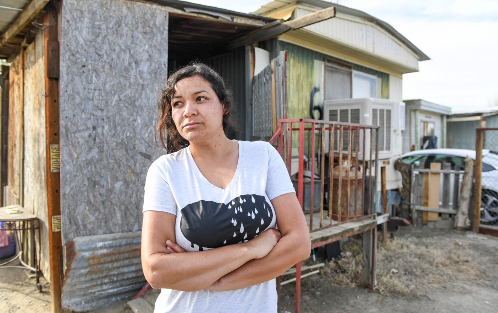 Carolina Navarro, 34, stands outside the mobile home she has been renting for the past 12 years, in Cantua Creek on Tuesday, March 2, 2021. Navarro is divorced with two children and has been out of work since November. Photo by Craig Kohruss/The Fresno Bee