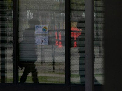 Silhouettes of students walking between buildings are seen reflected in a window at Ruby Bridges Elementary school in Alameda on March 16, 2021. Photo by Anne Wernikoff, CalMatters