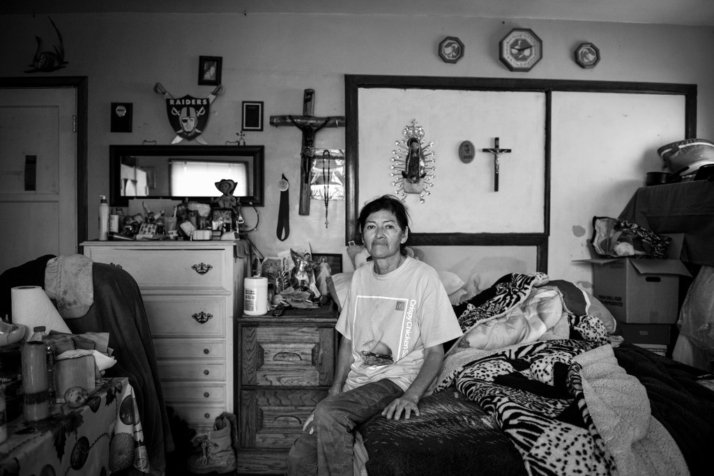 Teresa Herrera sits on her bed inside her bedroom, which has been converted into a small housing unit in Figueroa Place in Wilmington. Herrera has lived here for a decade, next to the Phillips 66 refinery. "I work so much that I don't have time to think about refineries or my health," Herrera, who works at McDonalds, said. "But at night, I do notice a strong smell." Photo by Pablo Unzueta