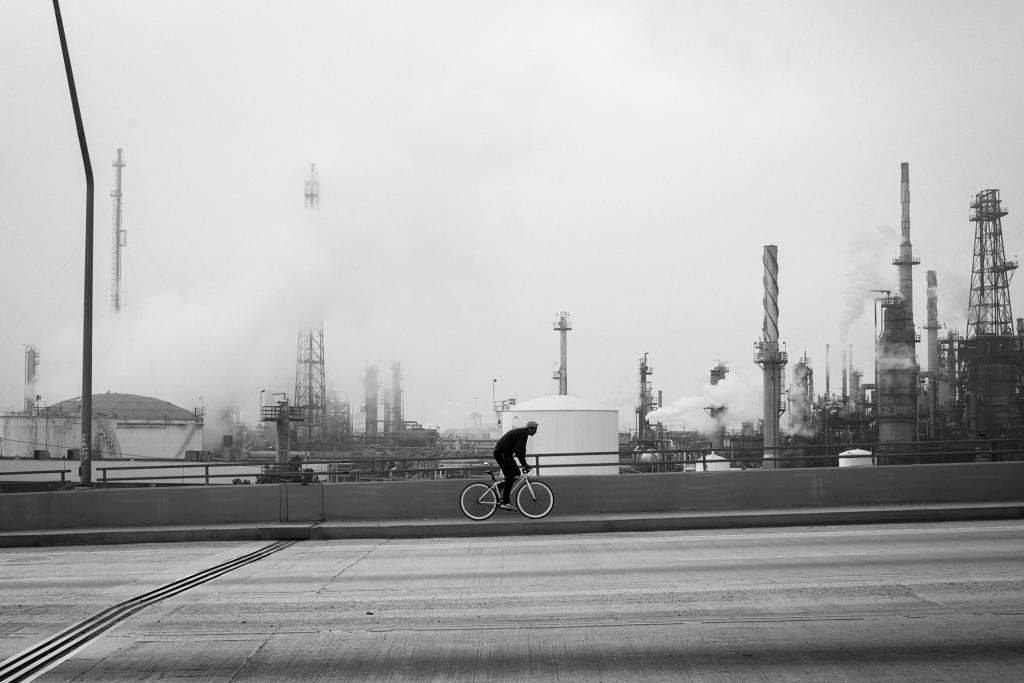 A cyclist rides by the Valero refinery in Wilmington on Anaheim Street on Nov. 7, 2021. According to the South Coast Air Quality Management District's date from 2018, the cancer risk in this sector is 985 per million. Photo by Pablo Unzueta