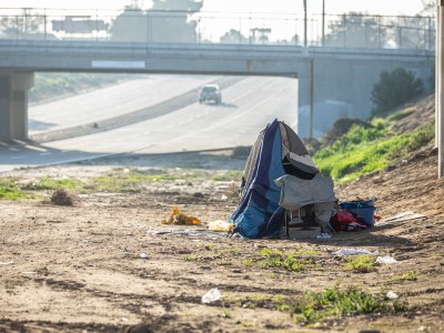 A homeless man's tent set up along the side of Golden State Boulevard just under Highway 41 in southwest Fresno on Feb. 11, 2022. Photo by Larry Valenzuela for CalMatters.