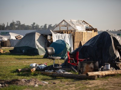 Tents and makeshift homes in a grassy area at a homeless encampment near Highway 180 in west Fresno on Feb. 11, 2022. Photo by Larry Valenzuela for CalMatters/CatchLight Local