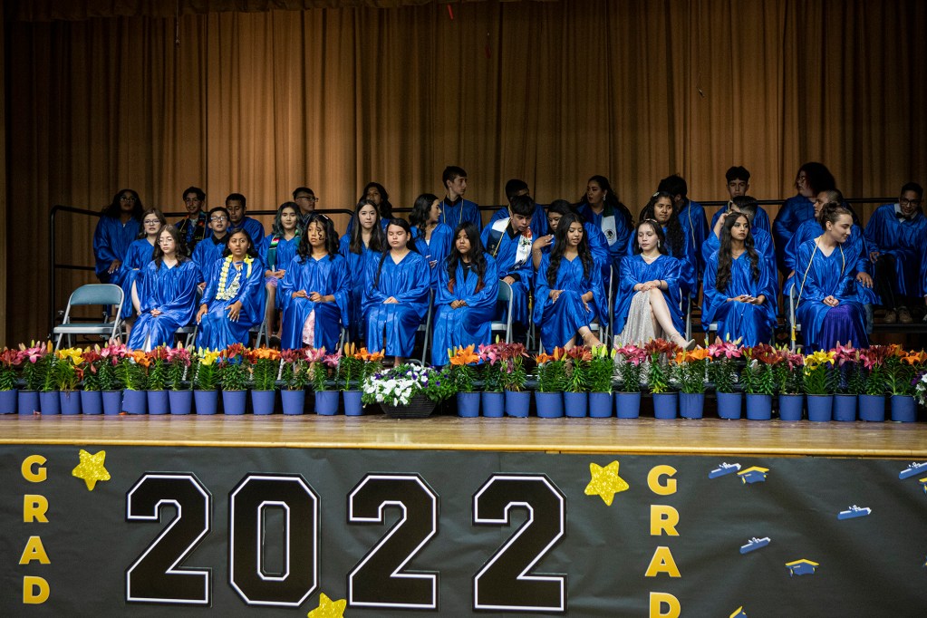 Students sit on stage for a group photo before the 8th-grade graduation ceremony at the Buttonwillow Union School gym on May 26, 2022. There are 33 students graduating from Buttonwillow. Photo by Larry Valenzuela for CalMatters