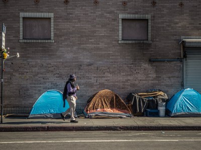A person walks by a homeless encampment in downtown Los Angeles on Nov. 18, 2022. Photo by Larry Valenzuela for CalMatters/CatchLight Local
