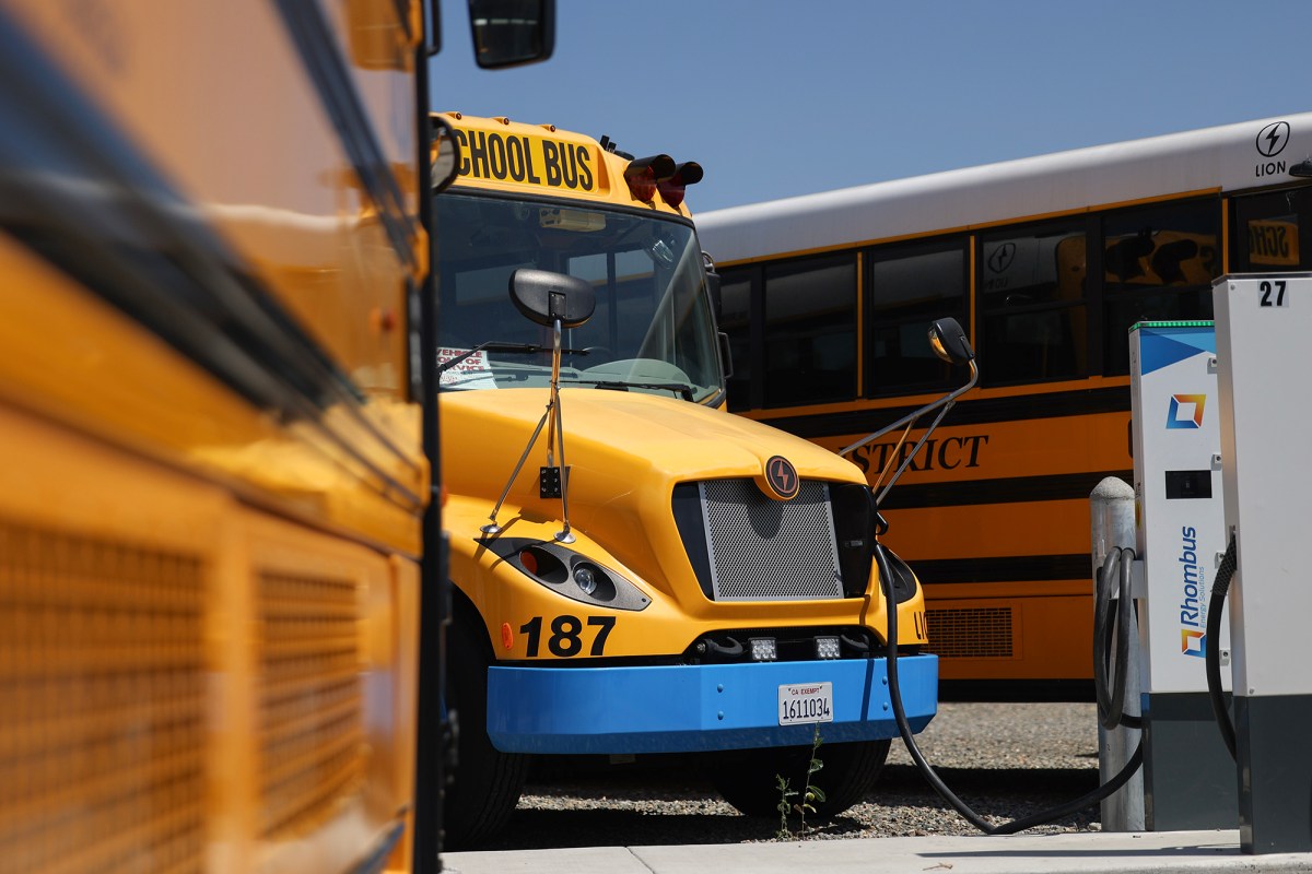 An electric school bus is charging at Grant Union High School in Sacramento on July 20, 2023. The chargers are bidirectional, which means they can feed power back to the electric grid. Photo by Miguel Gutierrez Jr., CalMatters