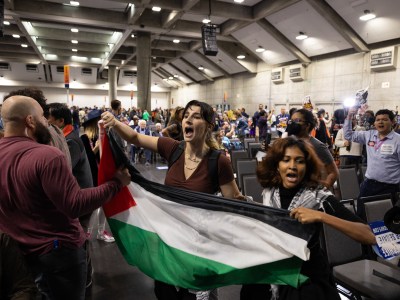 A security guard attempts to seize a Palestinian flag from protesters calling for a ceasefire of Israeli bombing in Gaza at the California Democratic Convention in Sacramento on Nov. 18, 2023. Photo by Miguel Gutierrez Jr., CalMatters