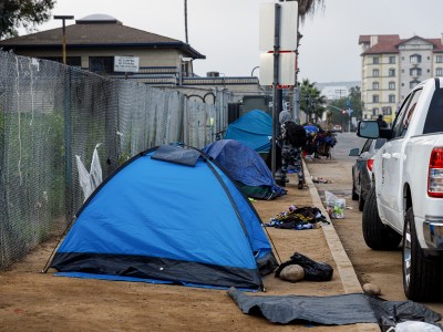 An encampment is seen on the sidewalk near a freeway entrance in downtown San Diego on March 22, 2024. Unhoused individuals moved their belongings across the street and later came back after cleaning finished. Photo by Kristian Carreon for CalMatters
