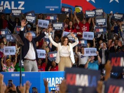 Vice President Kamala Harris and Minnesota Gov. Tim Walz wave their hands surrounded by a crowd of supporters waving placards in support of their presidential bid.