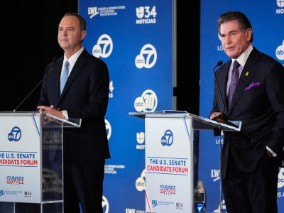 A close-up view of two people standing behind individual podiums on a stage during a debate